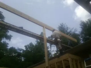 Carpenter setting a ridge beam over a new addition frame — Ice Dam Removal by Roofing Brothers in Grimsley