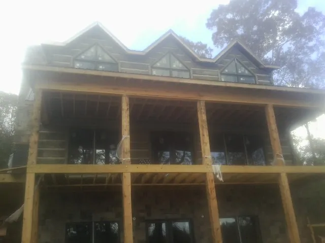 Dormers and porch framing on a large log home under construction — Roof Coating work by our crew in Grimsley