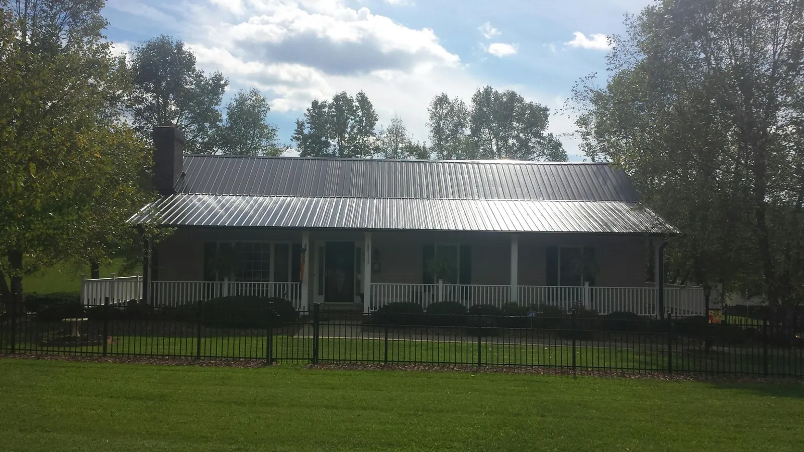 Gray metal roof on a brick ranch with a full width front porch — Gutter Guard Installation work by our crew in Grimsley