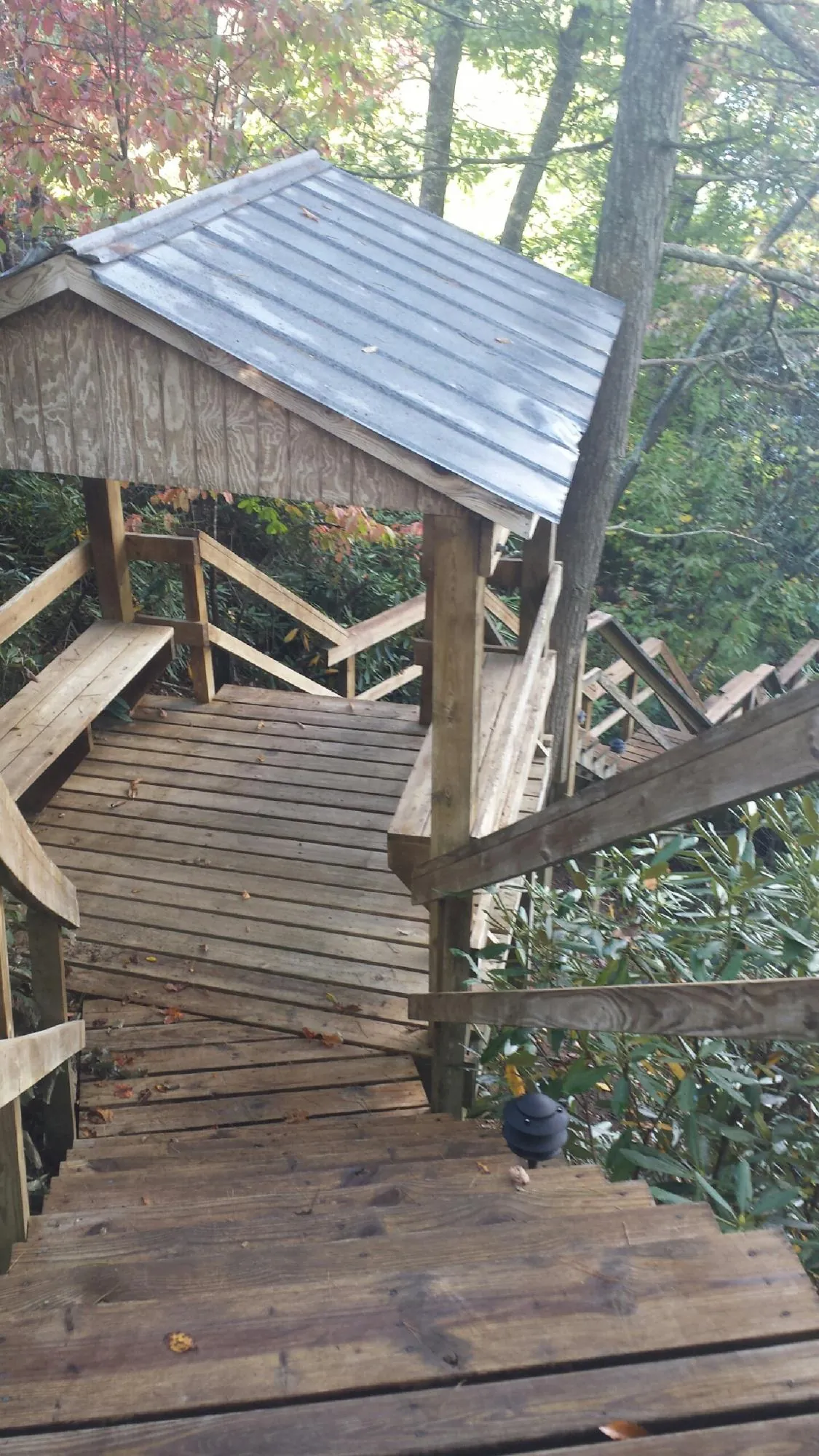 Metal roofed shelter over wooden steps on a wooded walkway — Skylight Repair & Installation work by our crew in Grimsley