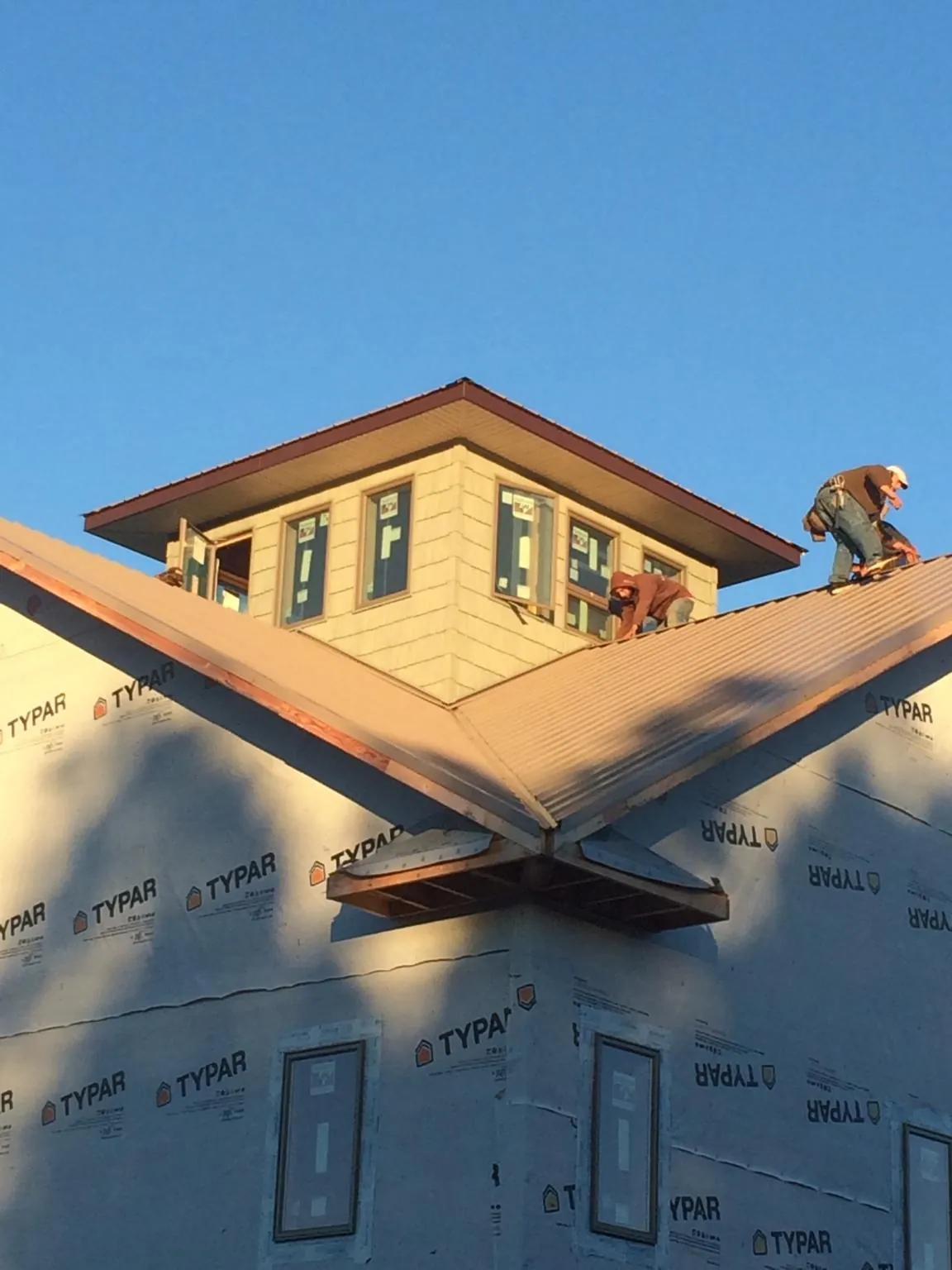 Roofers working around a rooftop cupola on a new metal roof at sunset — Roof Waterproofing in Grimsley by Roofing Brothers